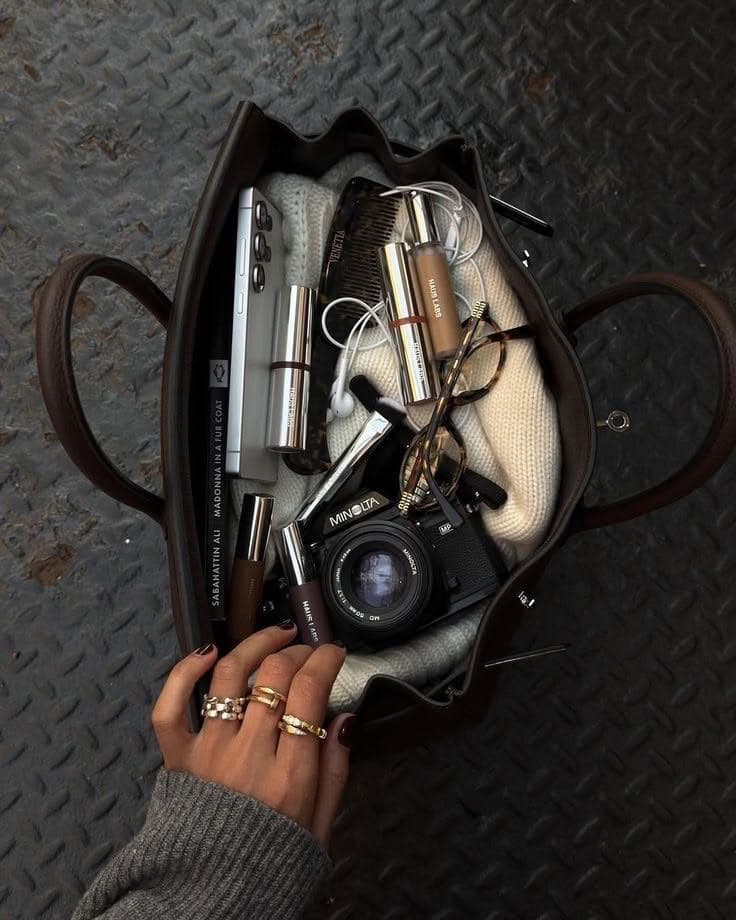 A travel bag with a camera, beauty essentials and a sweater